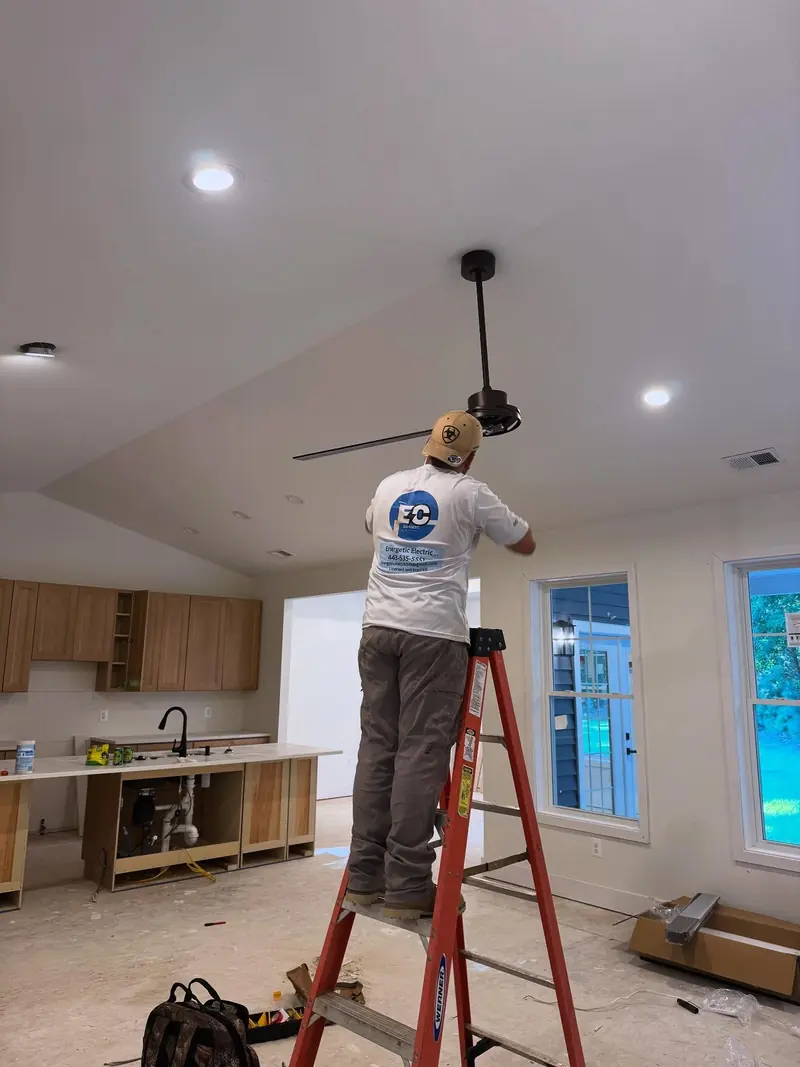 Energetic Electric electrician installing a ceiling fan in new construction